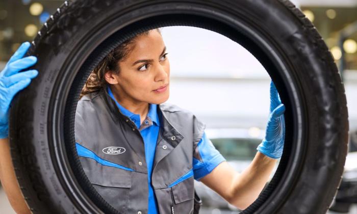 Frau am Reifenwechsel mit Ford Kleidung 